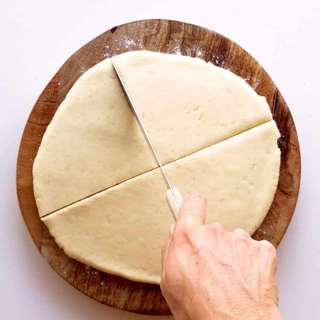 Slicing the dough into quarters with a knife.