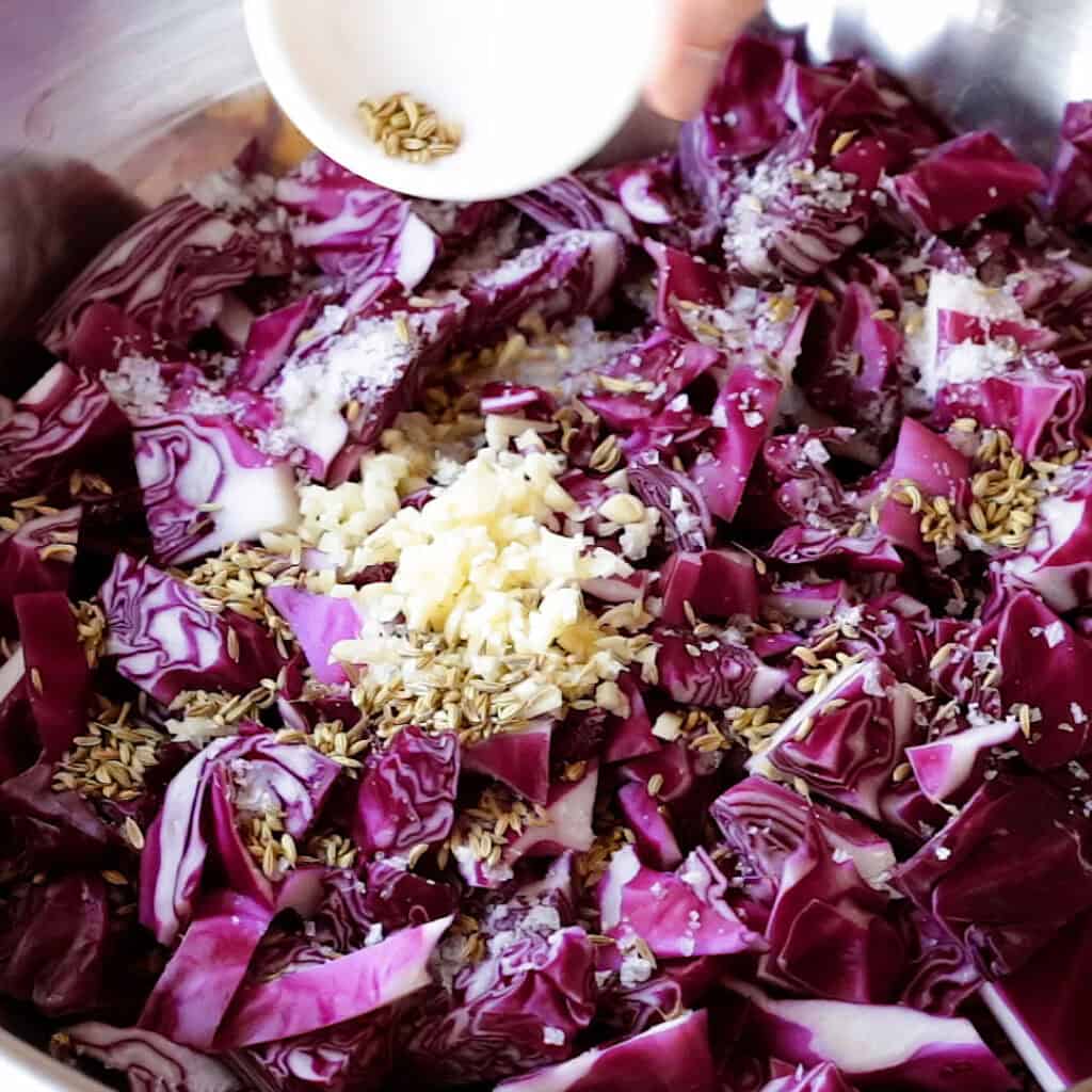 Adding the fennel seeds to the cabbage.