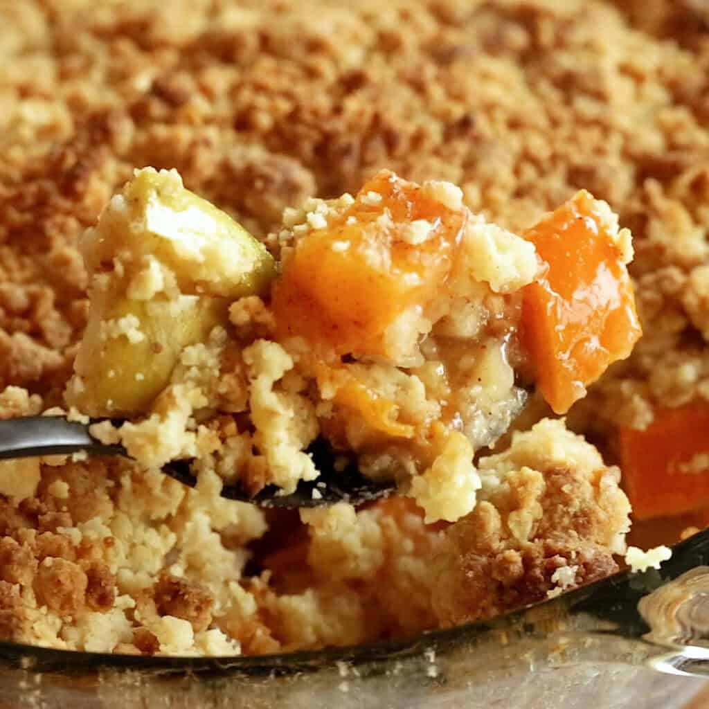 A large spoon scoops up persimmon crumble ready to serve.